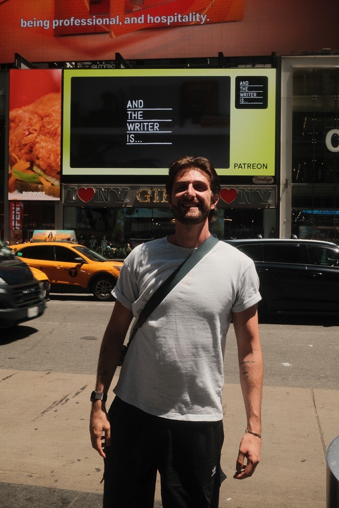 Jad Saad in New York under an And The Writer Is billboard